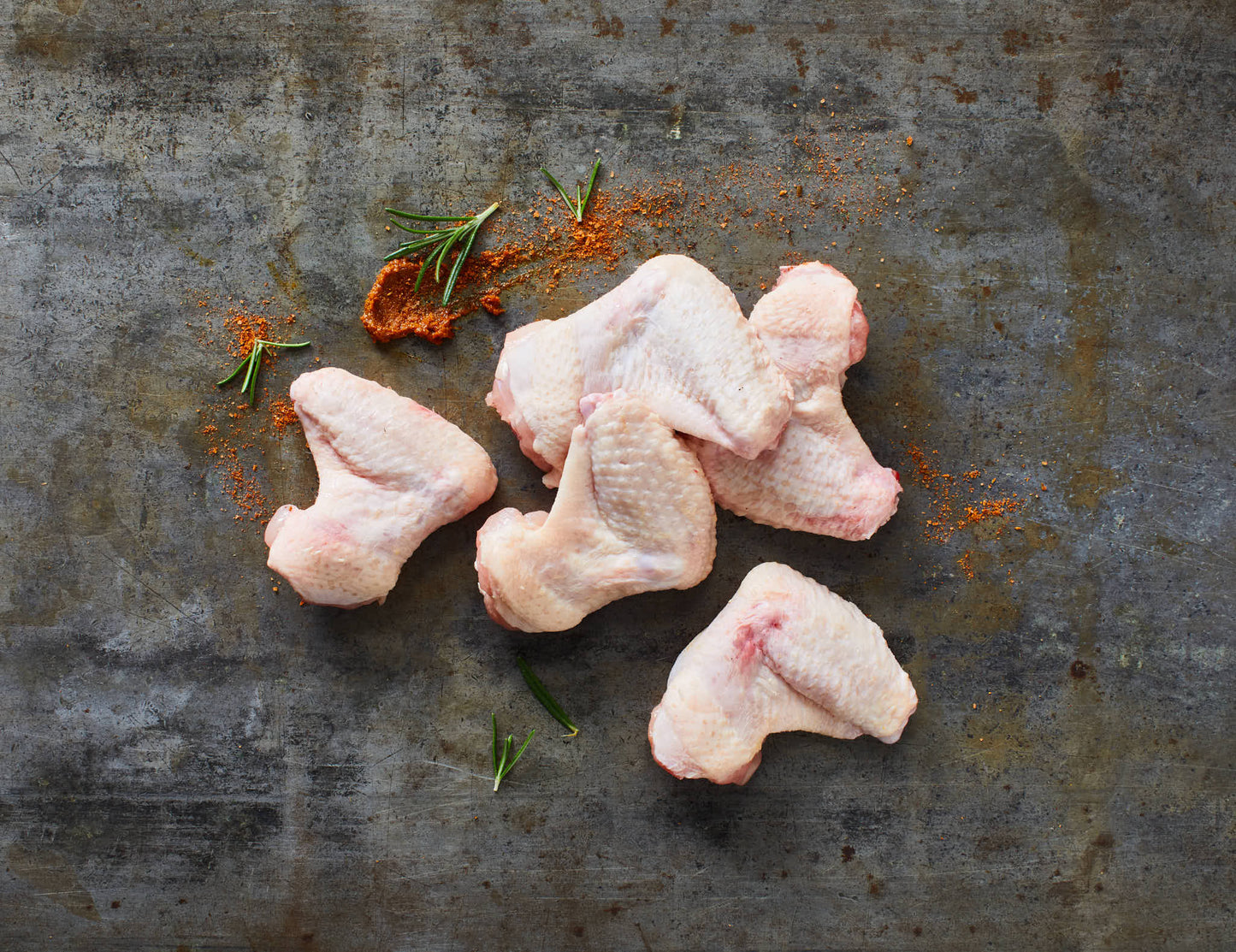Chicken Wings roh mit Gewürzen auf Steinplatte
