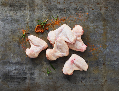 Chicken Wings roh mit Gewürzen auf Steinplatte